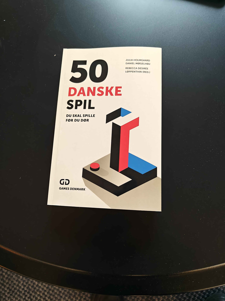 Book, "50 Danske spil du skal spille før du dør" by Games Denmark ontop of a table